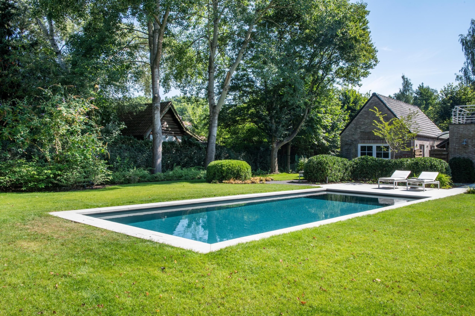 Bouwkundig zwembad met poolhouse op de achtergrond